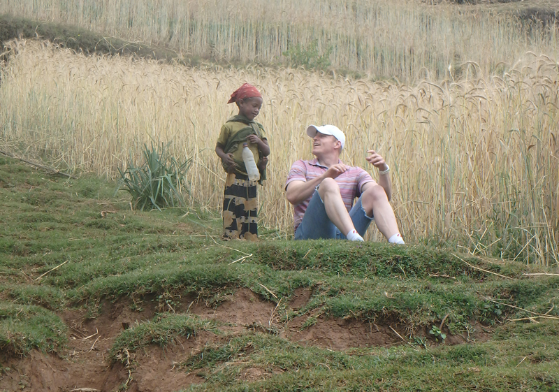 a man sitting in a field talking to a child