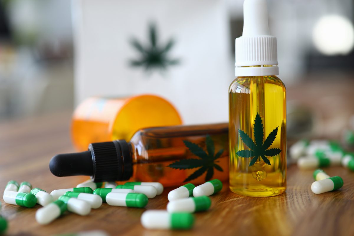 Close-up of medical marijuana products with capsules and cannabinoid oil in bottle with marihuana leaf on it. Pain medication for treatment. Medicine and healthcare concept