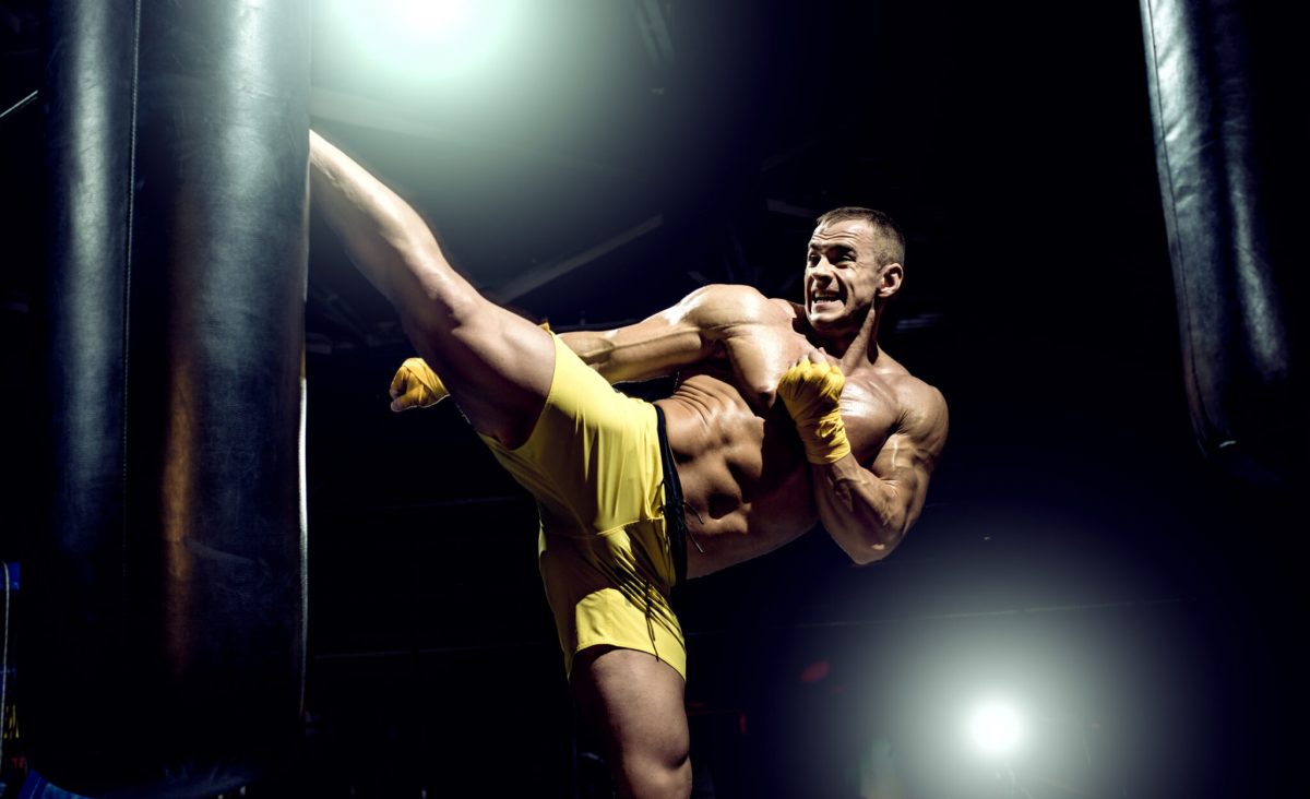 Thai boxer punch kick by punching bag, black bacground, horizontal photo