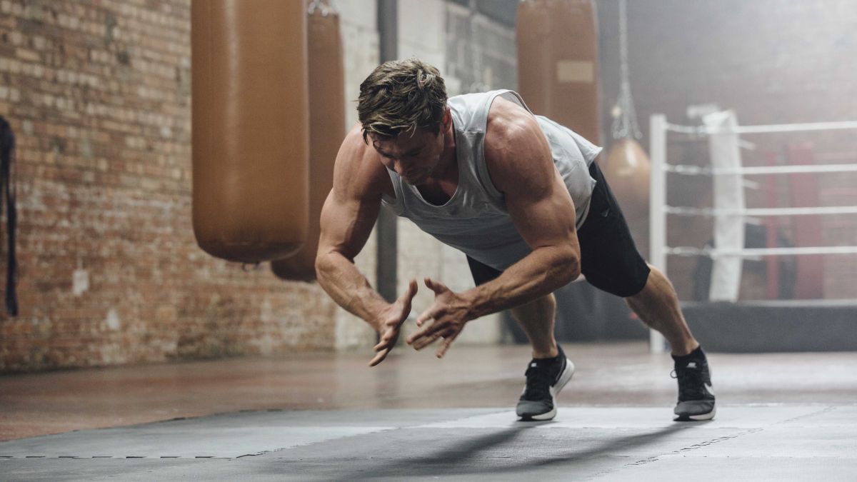 a fit man doing clapping pushups in a well lit gym space