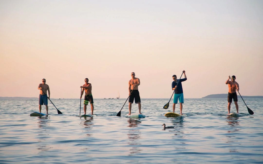 a group on SUP on the great lakes at sunset