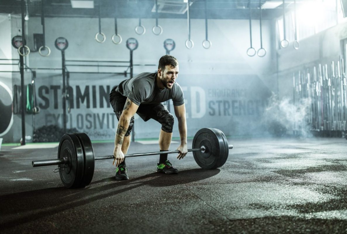 a man in a grey gym preparing to do a deadlift