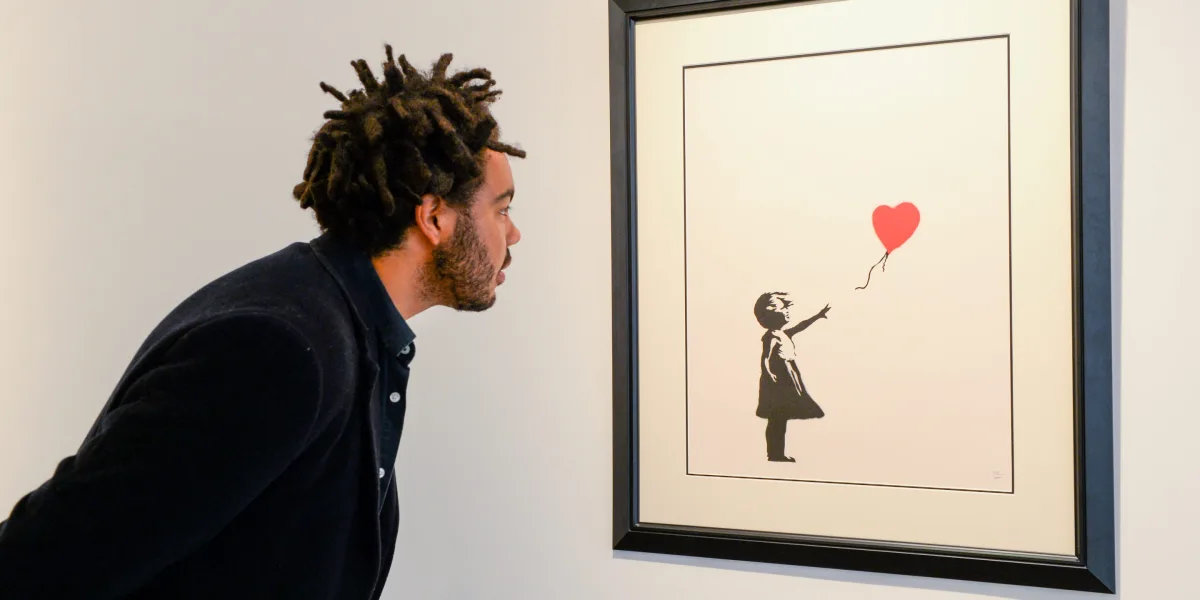 a man looking at a banksy piece of art