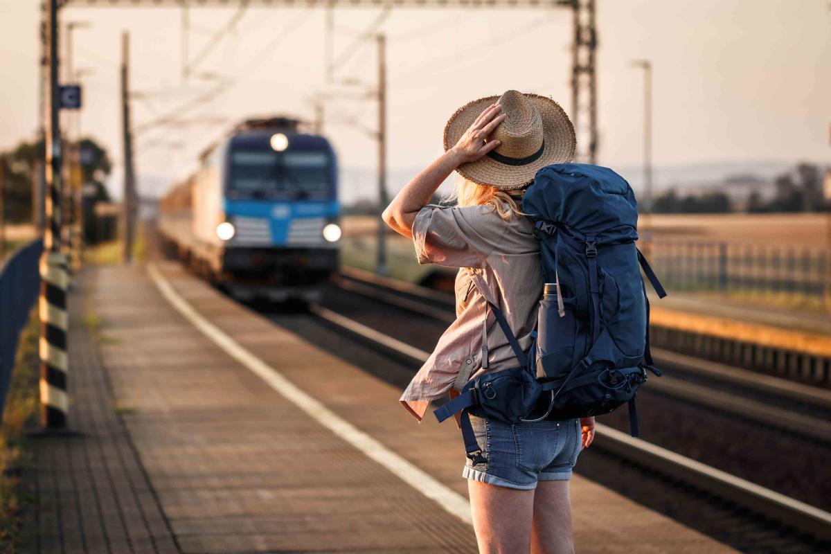 a woman in a hat with a backpack waiting for a train