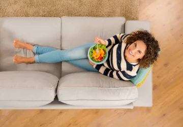a woman sitting on a couch with a healthy meal