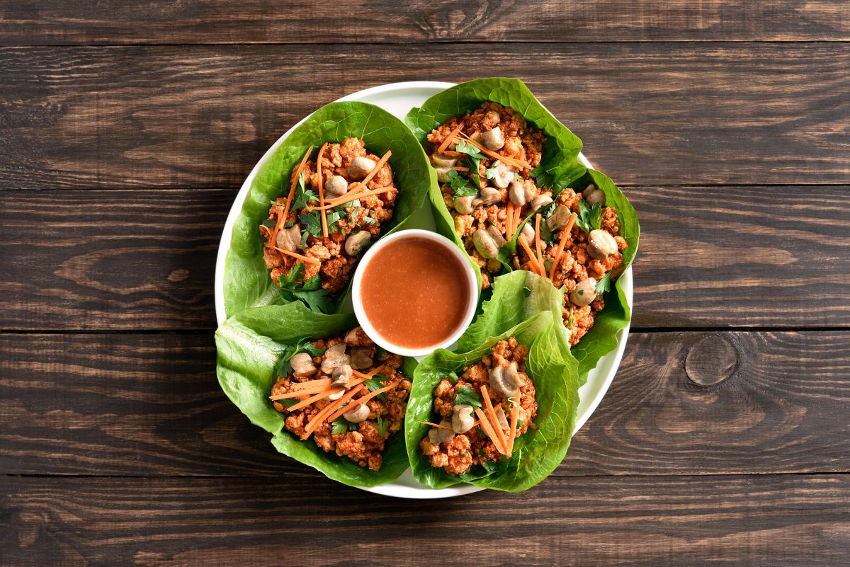Asian minced meat lettuce wraps on wooden background. Top view, flat lay