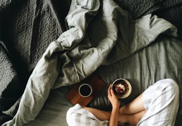 a woman sitting in her bed with a cup of coffee