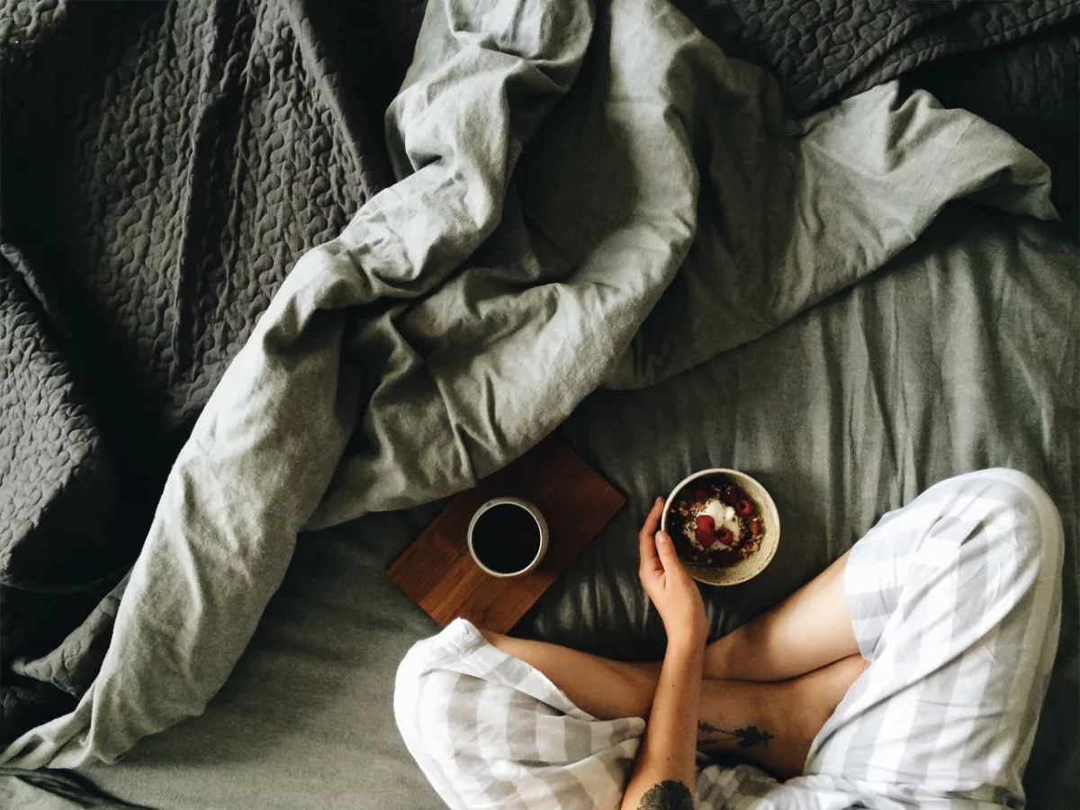 a woman sitting in her bed with a cup of coffee
