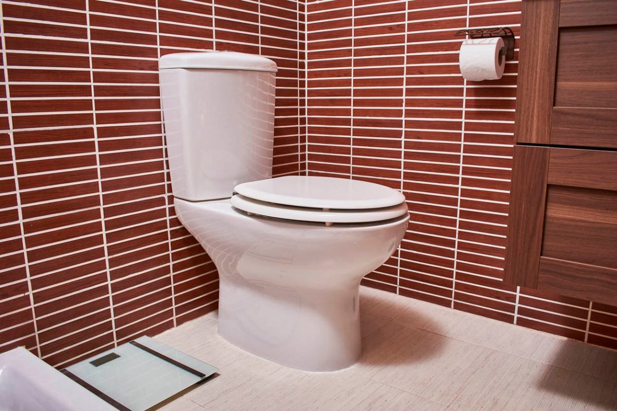 a toilet in a brown tiled room