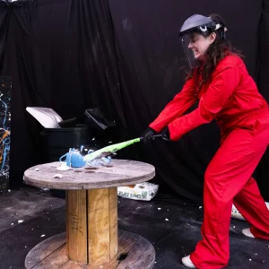 a woman in coveralls smashing a table
